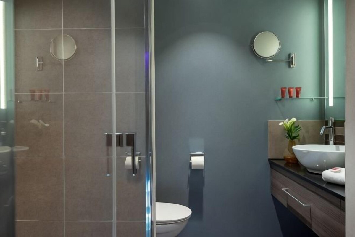 Un baño moderno con cabina de ducha de vidrio, inodoro, lavabo con espejo y toallero.