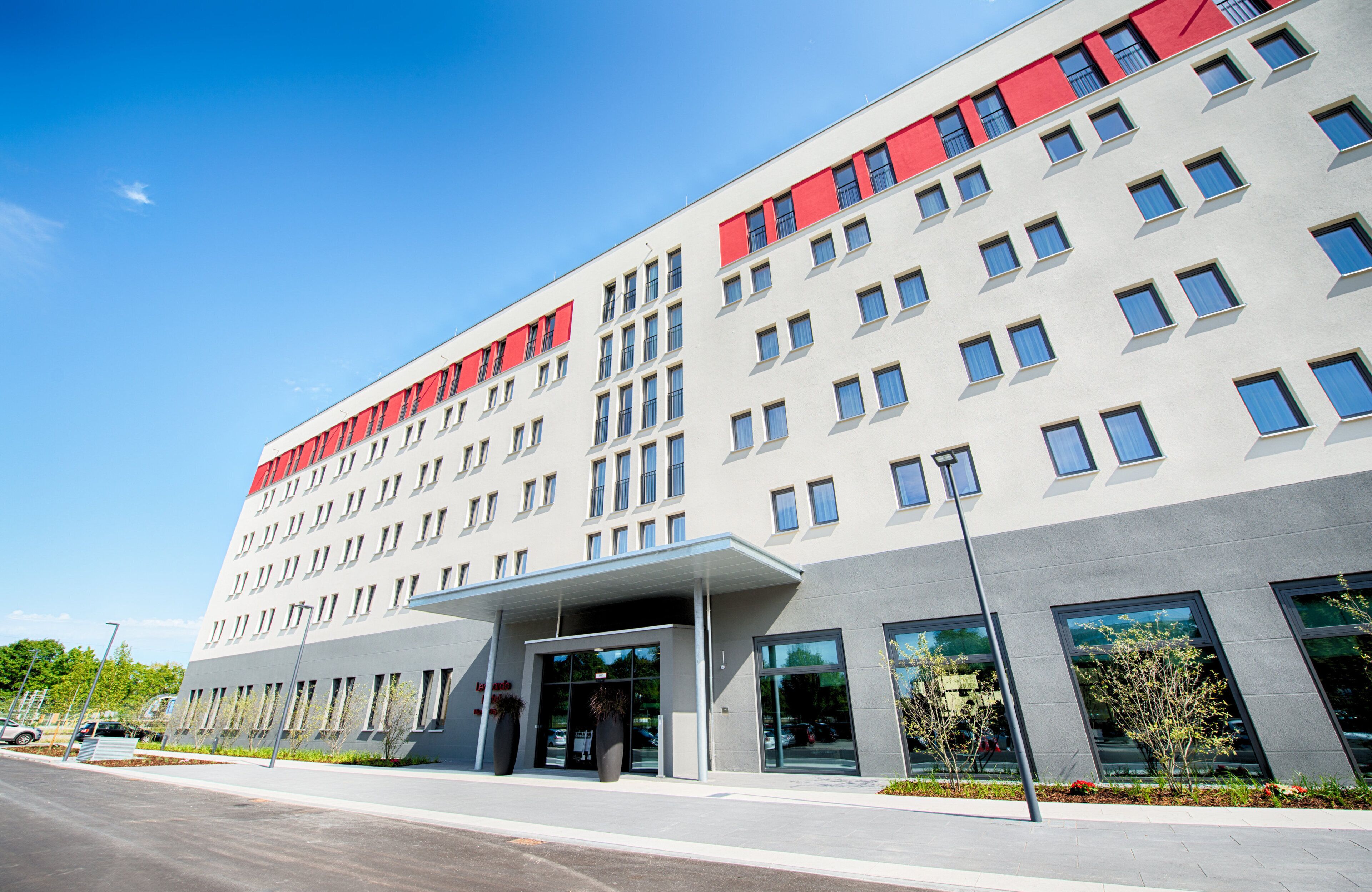 Ein modernes, mehrgeschossiges Hotel mit schlichter Fassade, großen Fenstern und einem markanten Eingang mit einer überdachten Wegeführung.