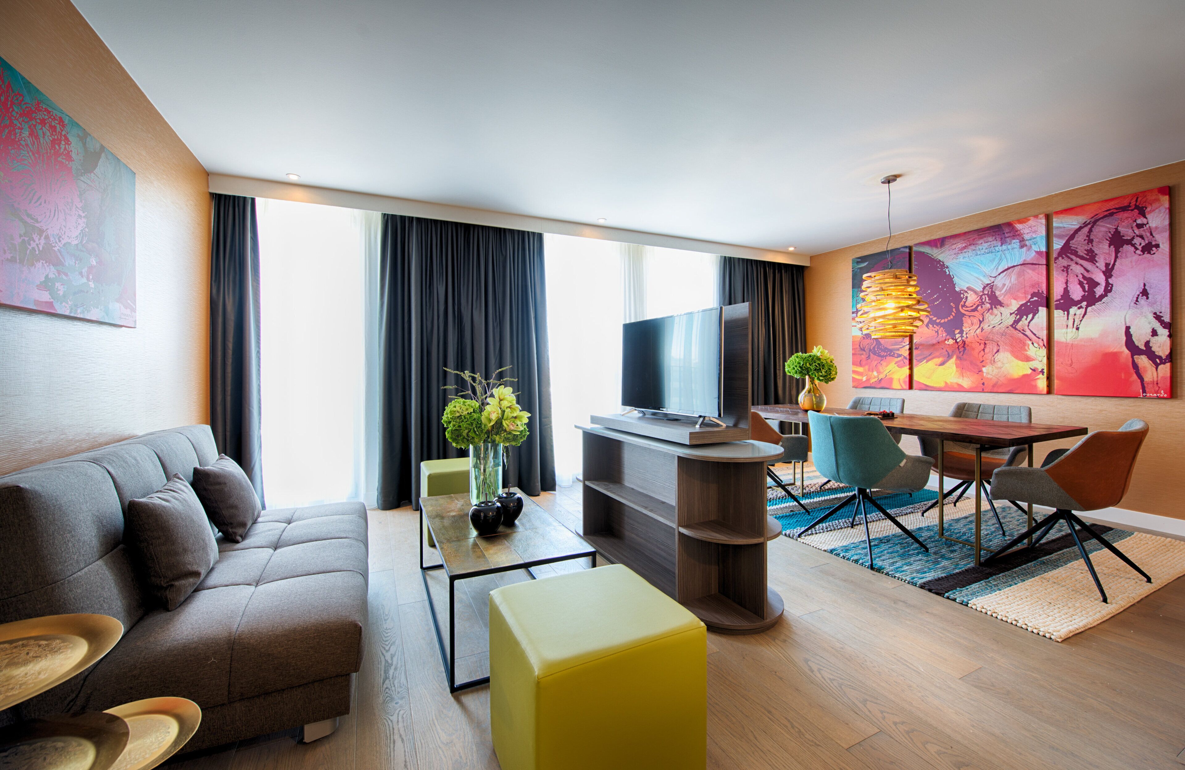 Una sala de estar moderna con sofá, mesa de centro, televisor y comedor con sillas y mesa.