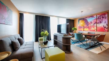 Una sala de estar moderna con sofá, mesa de centro, televisor y comedor con sillas y mesa.