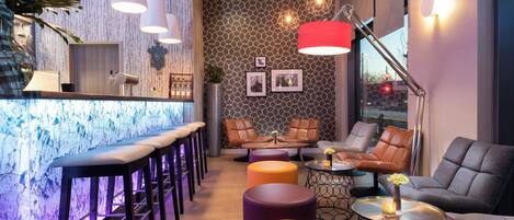 Uma área de bar moderna com banquetas, balcão e assentos, parede estampada e iluminação pendente.