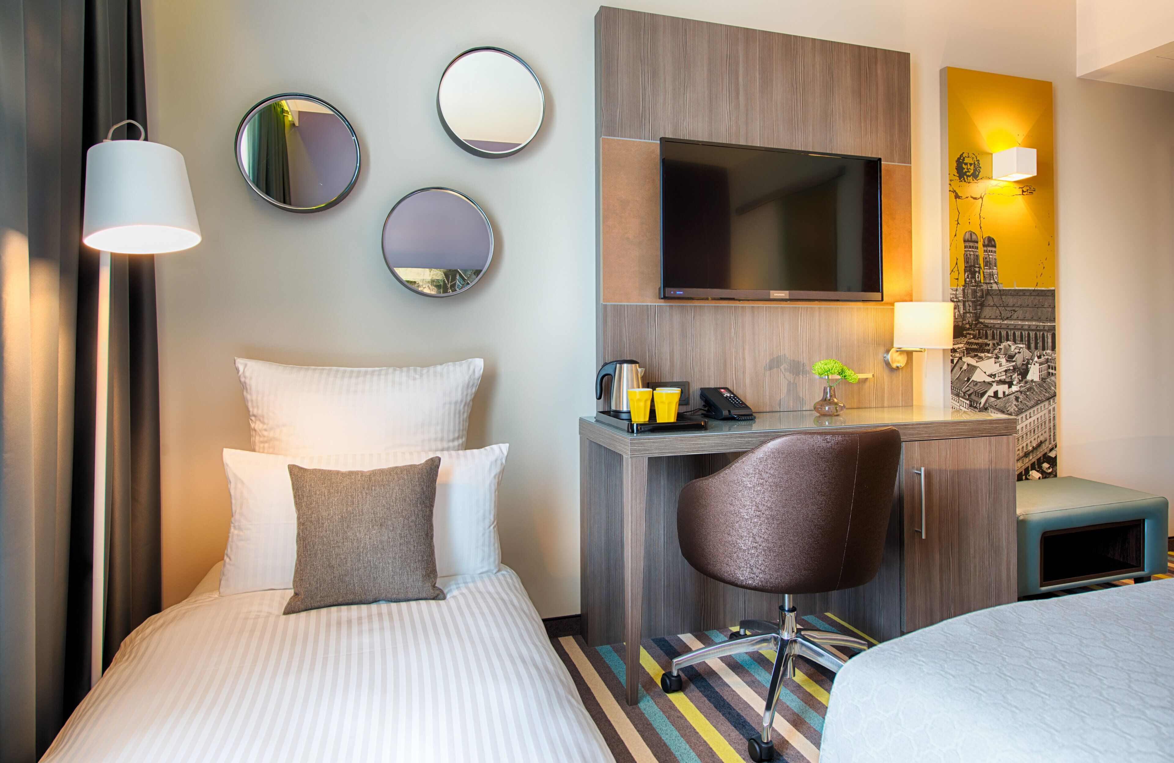 Ein Hotelzimmer mit Bett, Schreibtisch, Stuhl, Fernseher und Spiegel.
