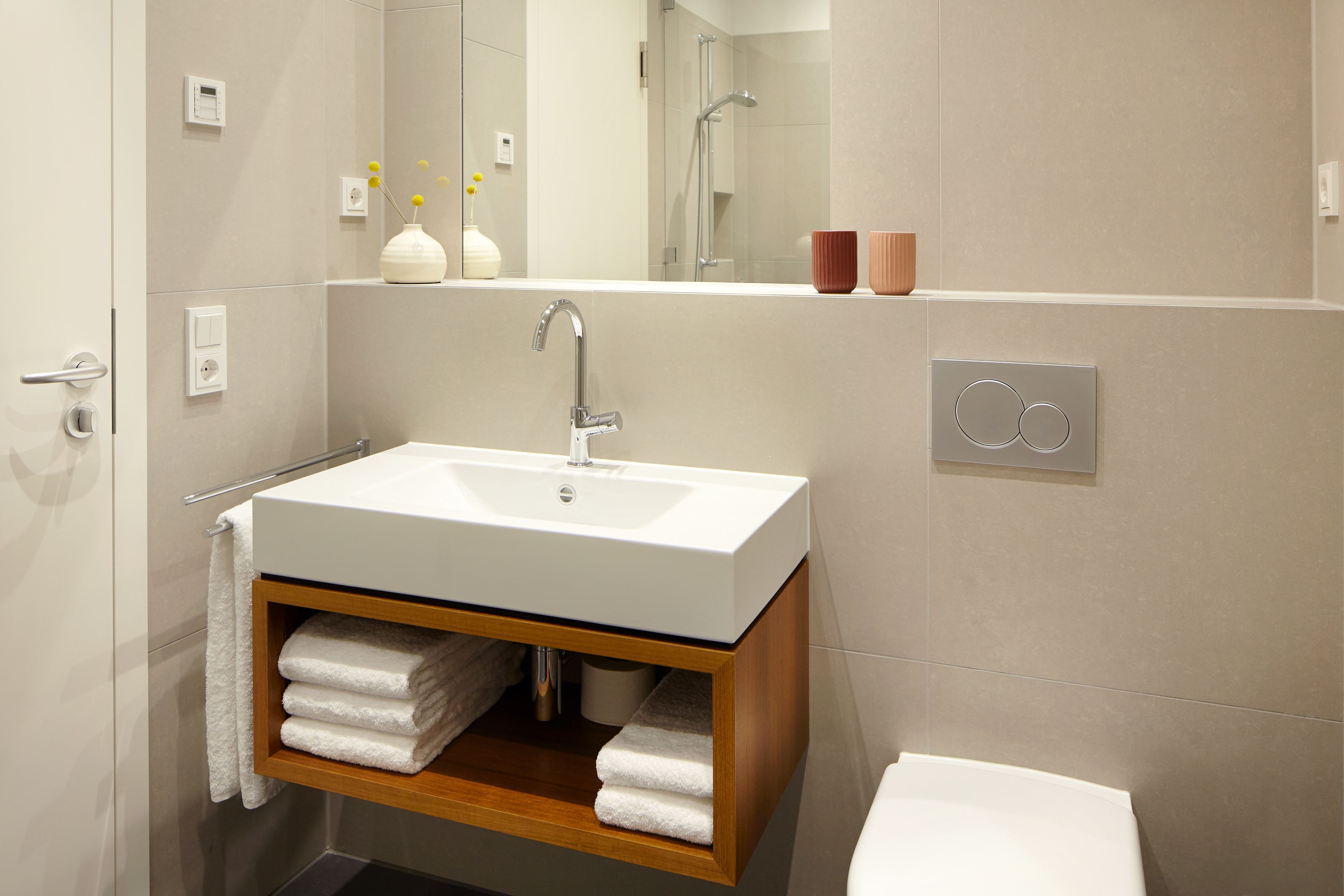 A modern bathroom with a white sink, wooden vanity, and a toilet.