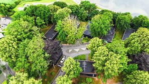An aerial view of a residential area with a central roundabout, surrounded by lush greenery and houses with dark roofs. - Glück in Sicht (Gluecksburg)