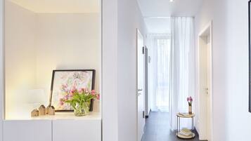 A modern hallway with a framed picture, a vase with flowers, and a small table with books.