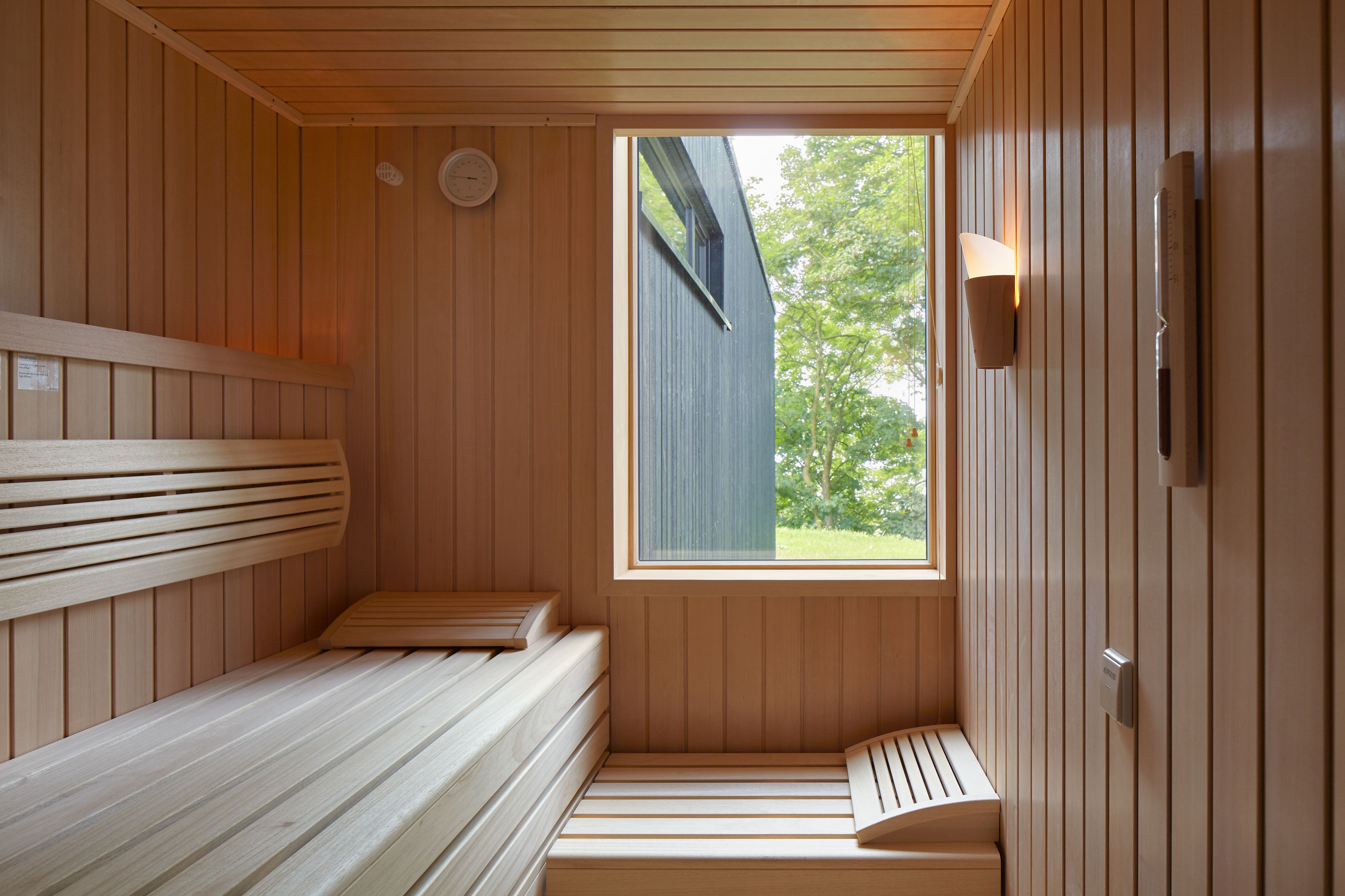 A sauna with wooden benches and a window providing a view of the outdoors.