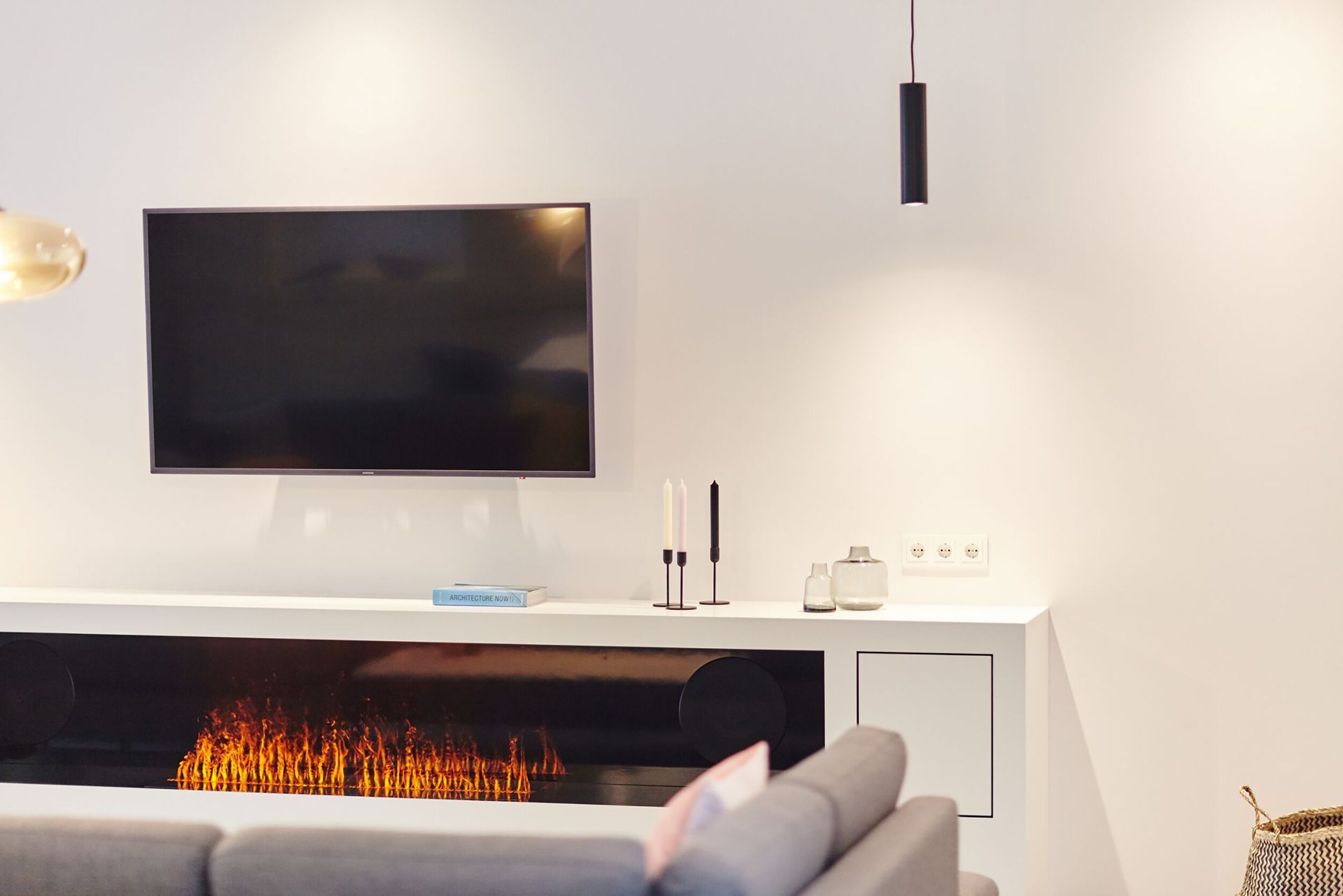 A modern living room with a flat-screen TV, a fireplace, a sofa, and a minimalist console table.