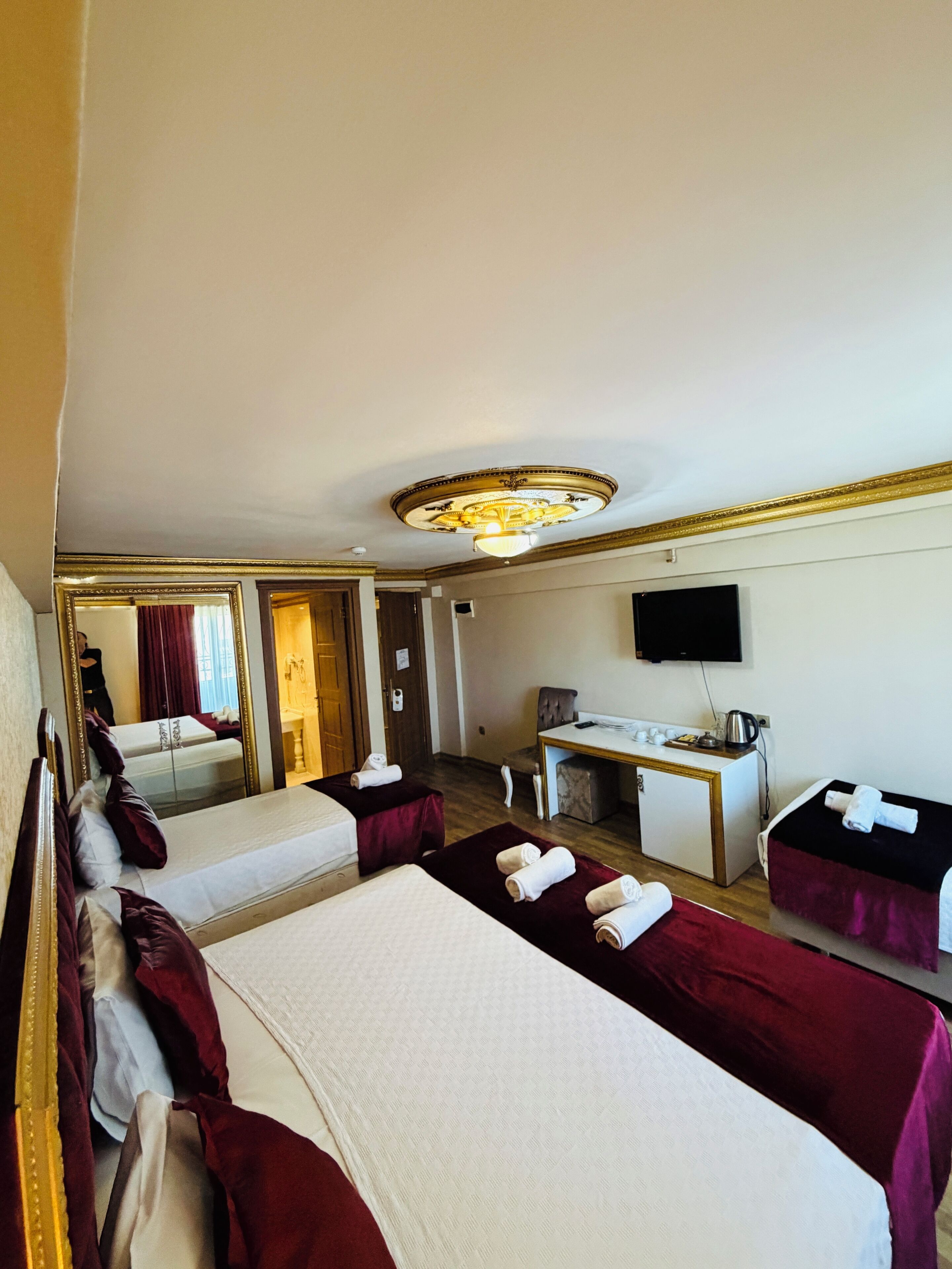 A hotel room with two beds, a desk, a television, and a mirror.