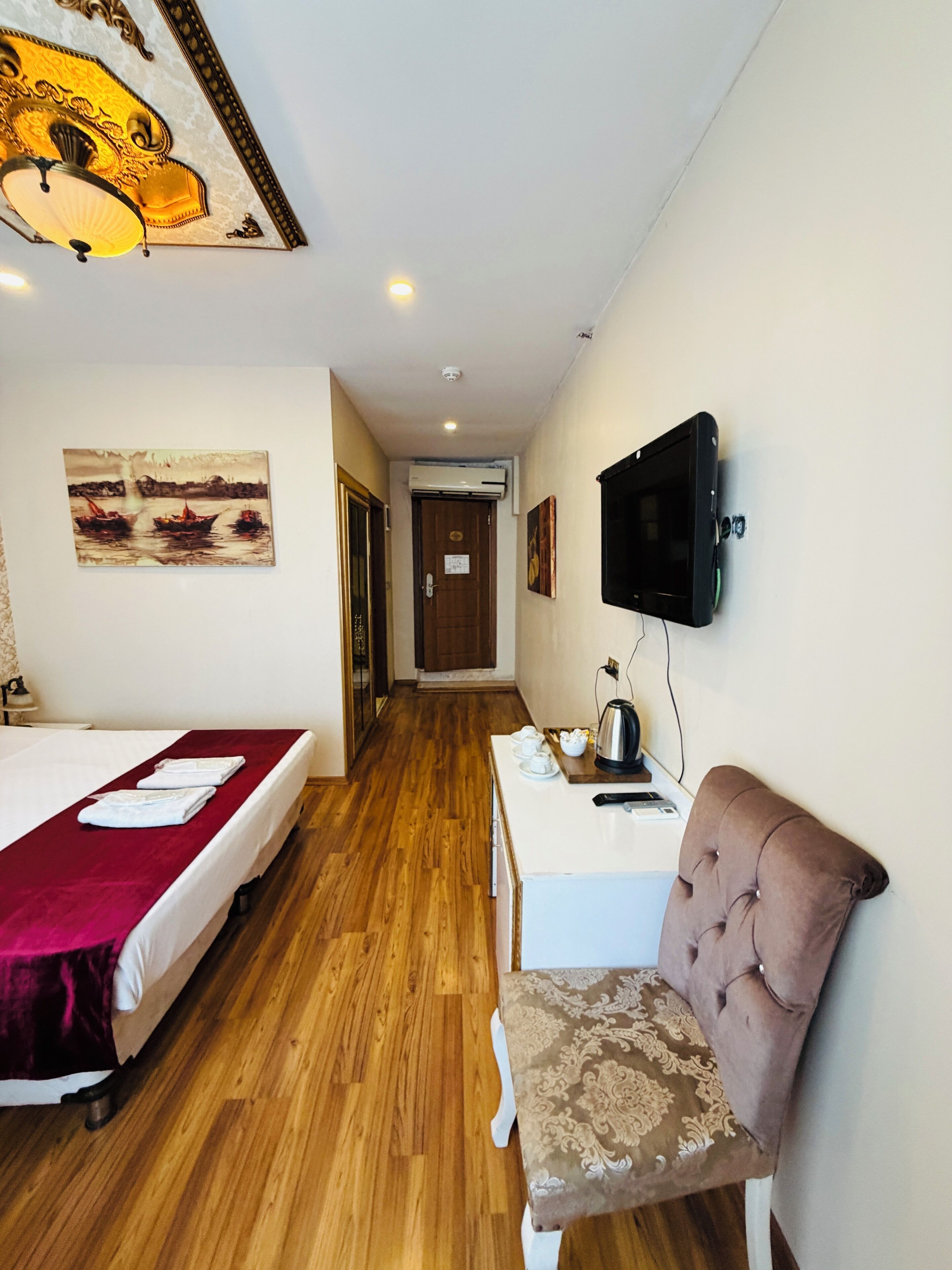 A hotel room with two beds, a television, a coffee table, and artwork on the walls.