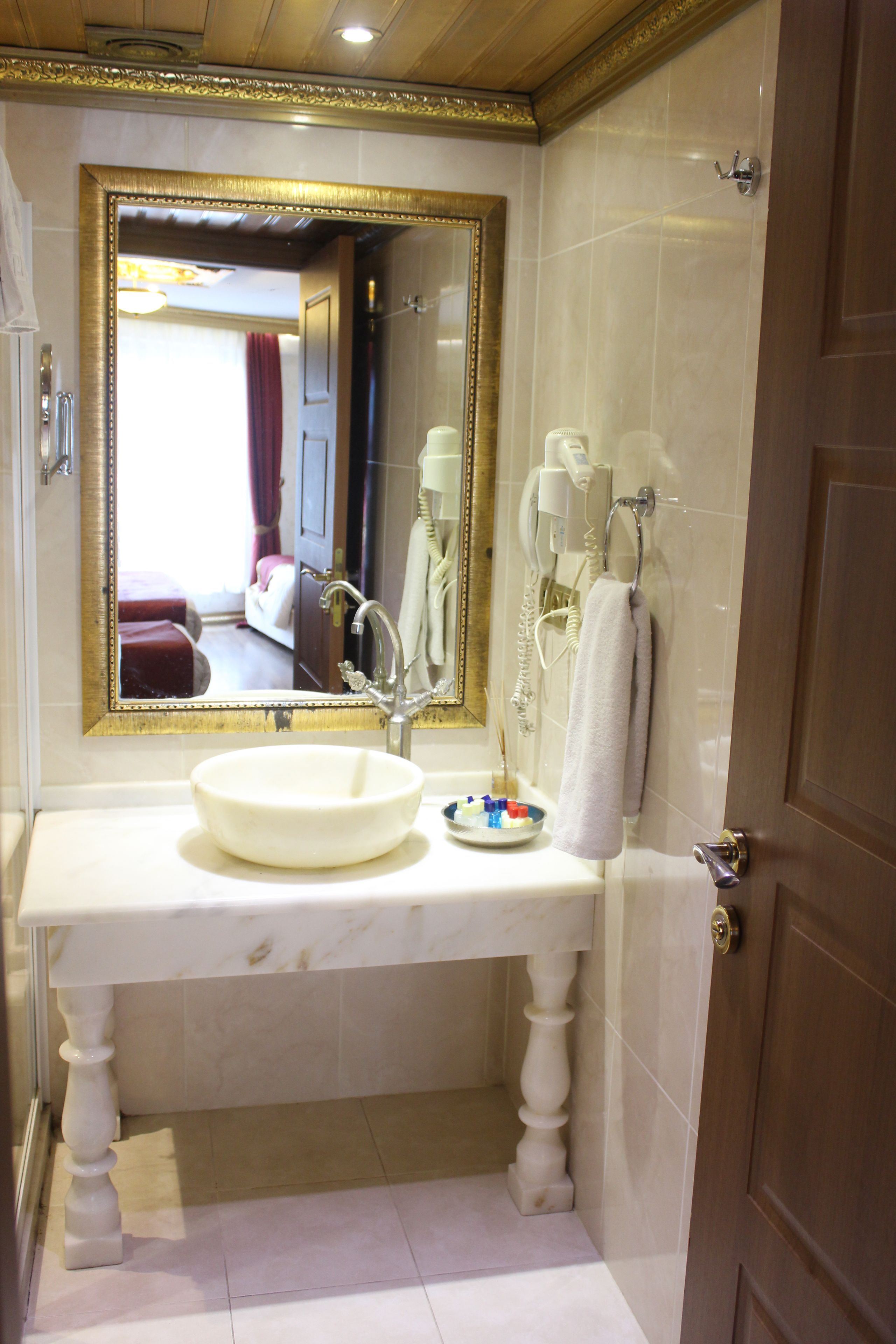 A bathroom with a large mirror, a sink, a towel rack, and a shower area.