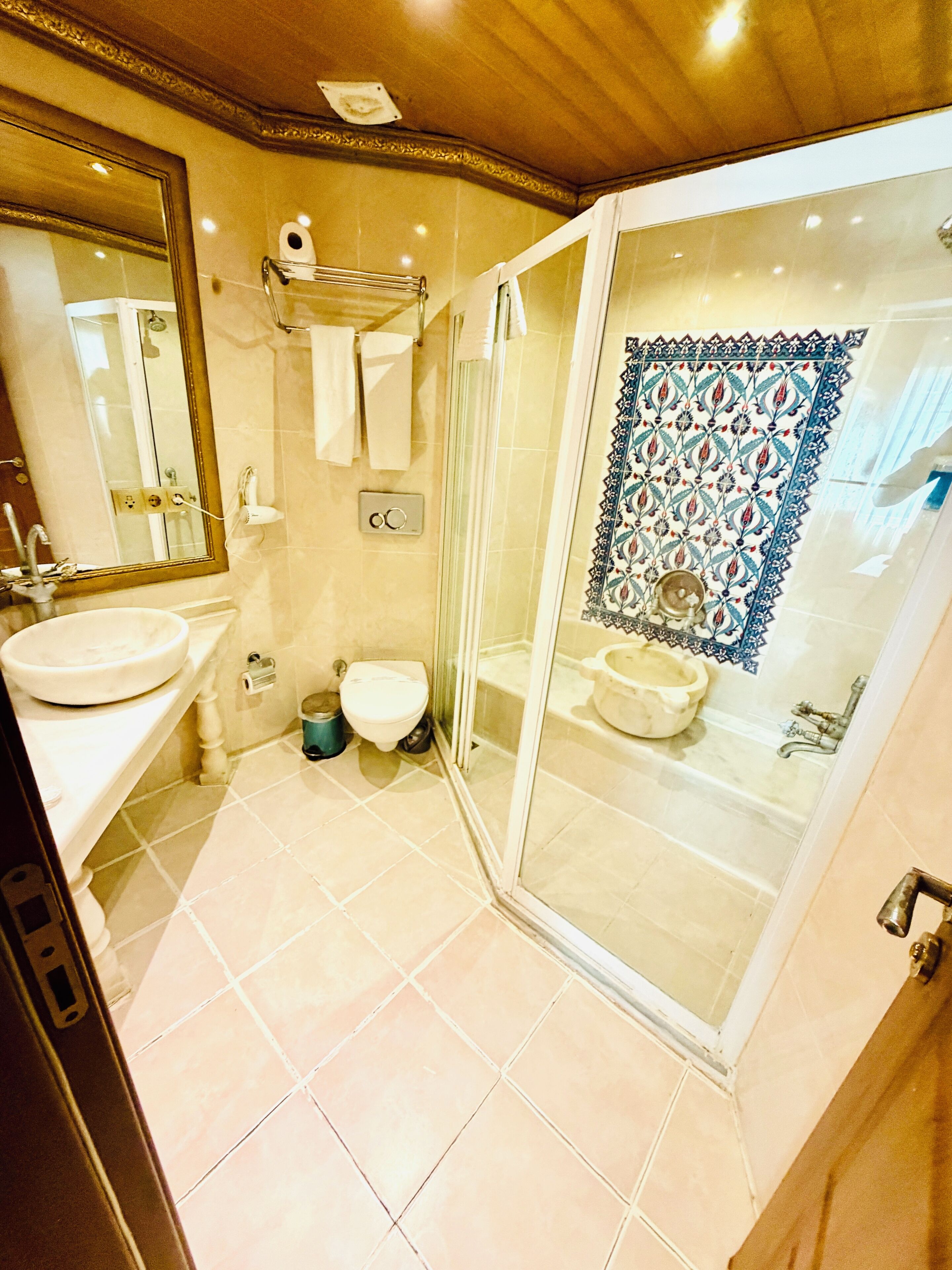 Ein Badezimmer mit Duschkabine, Waschbecken, Toilette und Spiegel.