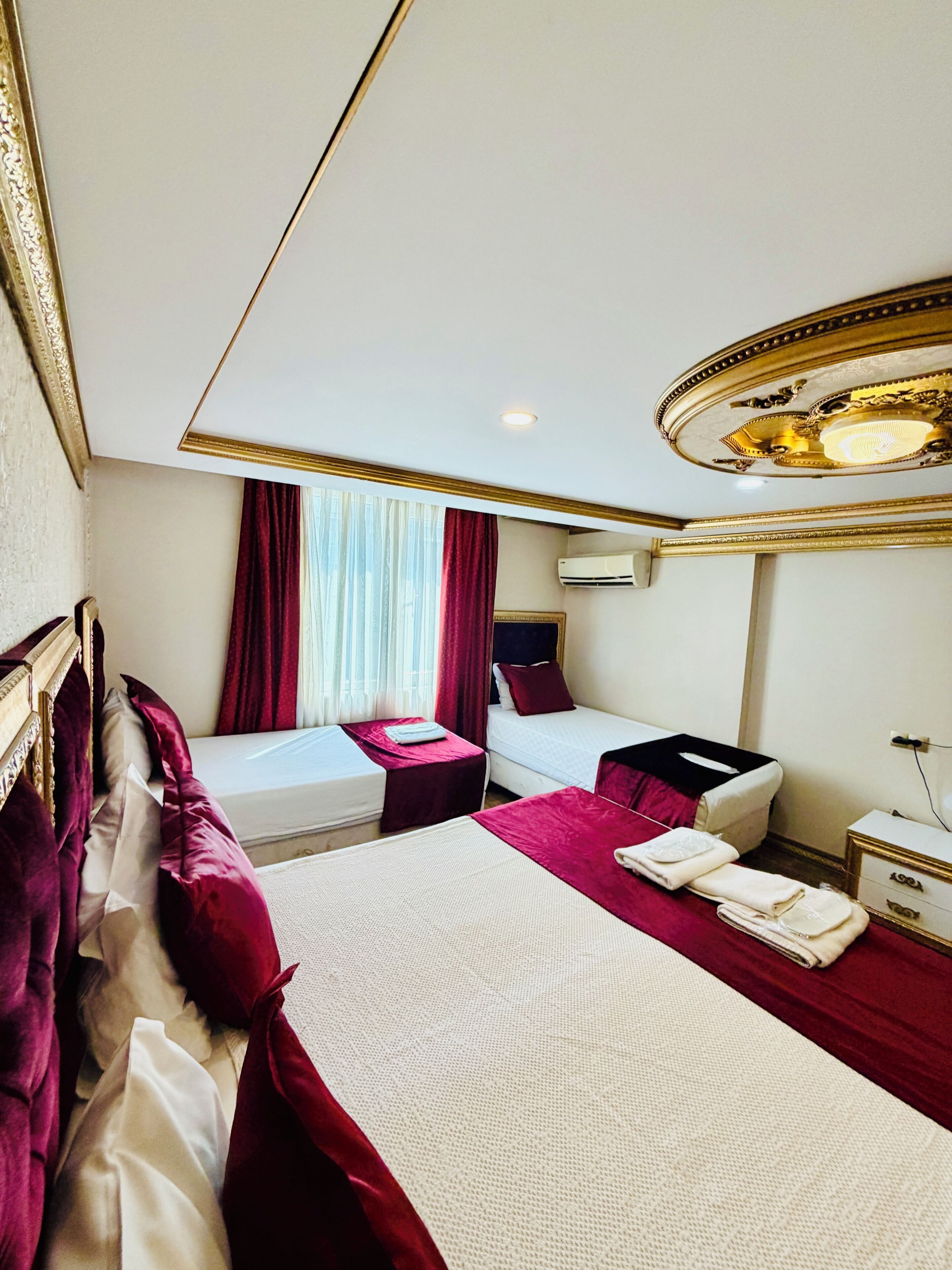 A hotel room with two beds, a vanity with a mirror, and a ceiling light fixture.