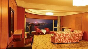 A hotel room with a bed, a desk, a chair, and a view of a cityscape at night. - Qingdao Donghai Hotel (Qingdao)