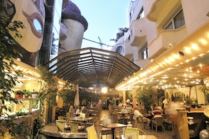 An outdoor café with tables and chairs, surrounded by buildings with unique architecture.