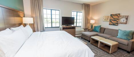 Una habitación de hotel con una cama grande, un sofá, un televisor y una mesita.
