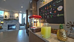 Un espace bar agrémenté d’une cheminée en pierre, d’un tableau noir où sont affichées les annonces concernant les événements, et d’une grande décoration en forme d’ananas.