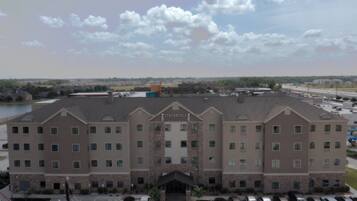 A Staybridge Suites hotel with a central entrance, parking lot, and a view of the surrounding area.
