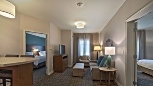 Une chambre d’hôtel avec un lit, un bureau, un canapé et une télévision.
