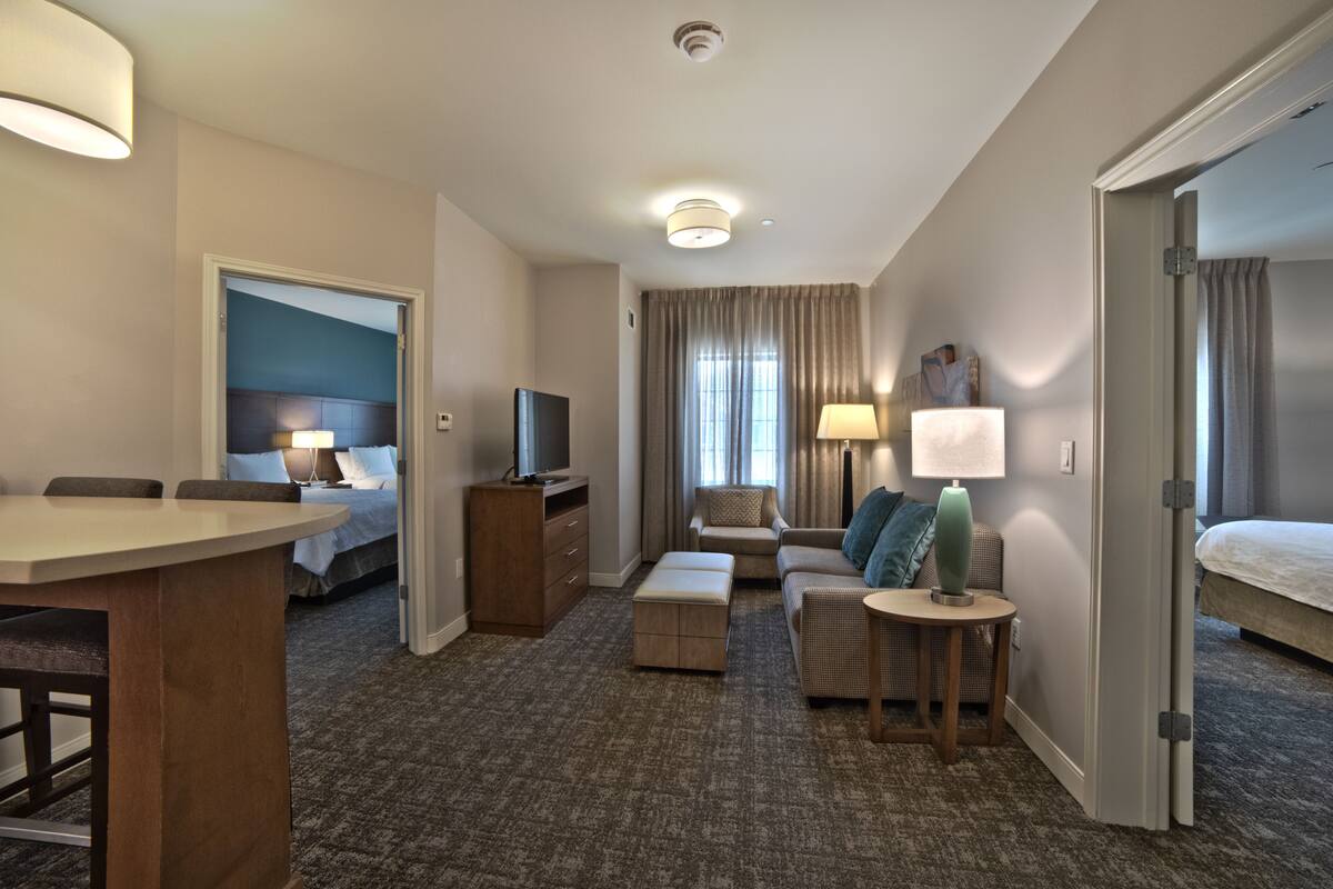 Une chambre d’hôtel avec un lit, un bureau, un canapé et une télévision.