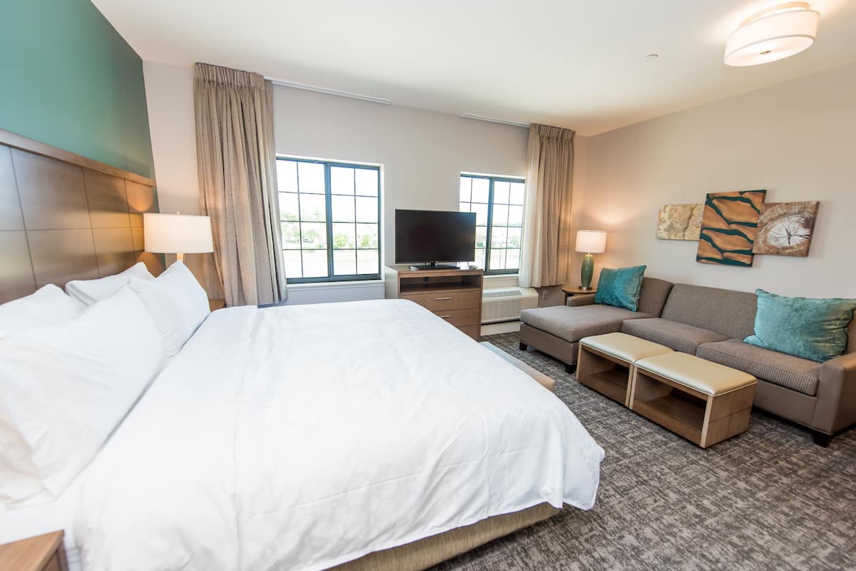 Une chambre d’hôtel avec un grand lit, un canapé, une télévision et un bureau.