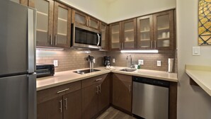 Une cuisine moderne avec des meubles en bois, des appareils électroménagers en acier inoxydable et un four à micro-ondes.