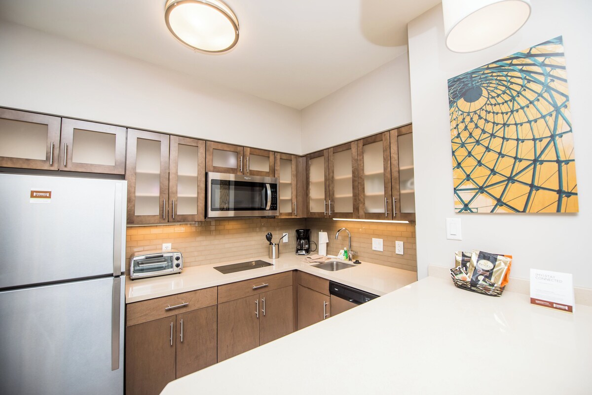 A modern kitchen with stainless steel appliances, wooden cabinets, and a large window.