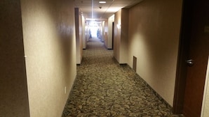 A long, narrow hallway with patterned carpet and beige walls. - Crivitz Lodge (Crivitz)