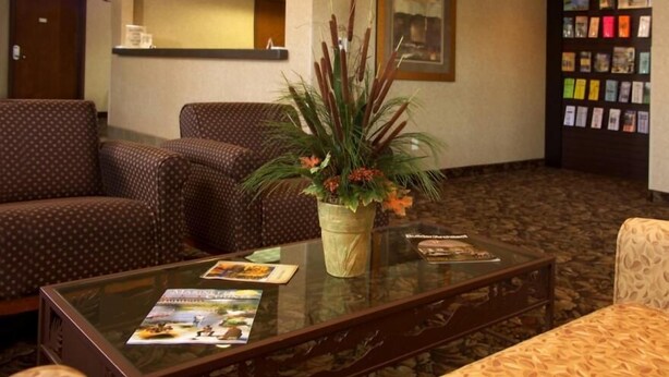 A lobby with patterned furniture, a glass coffee table with brochures, and a plant centerpiece. - Crivitz Lodge (Crivitz)