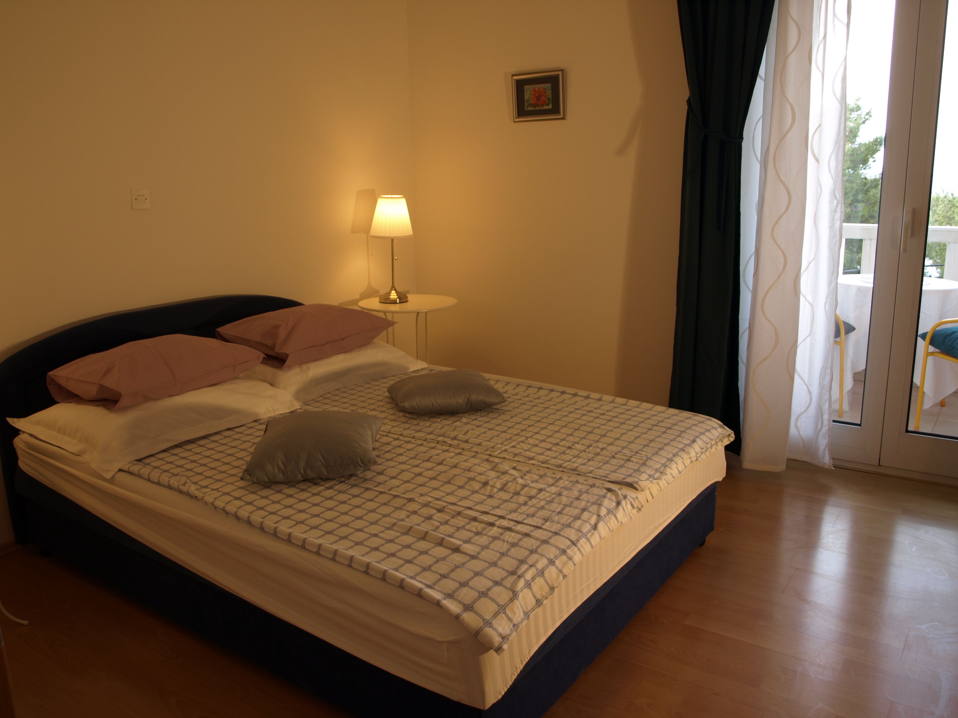 A neatly made bed with a patterned bedspread, two pillows, and a bedside lamp.