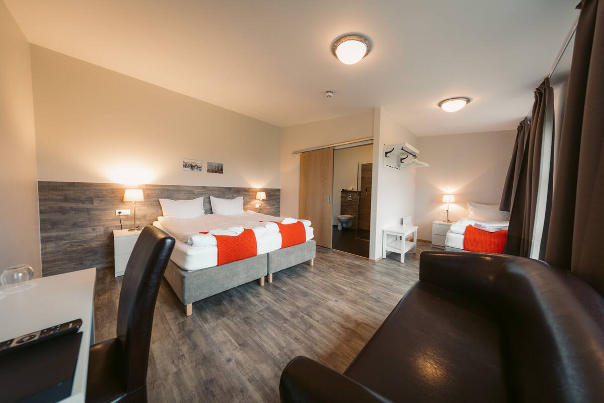 Una habitación de hotel moderna con cama, mesitas de noche, escritorio y una silla.