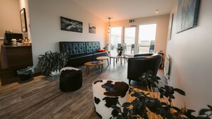 A modern living room with a sofa, coffee table, and a large window. - Hotel Vos (Rangarthing ytra)