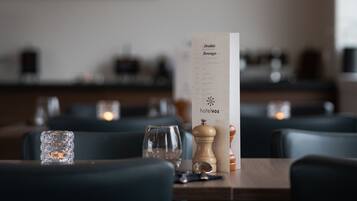 Interior de un restaurante con un menú sobre la mesa, iluminación tenue y un cuadro en la pared.