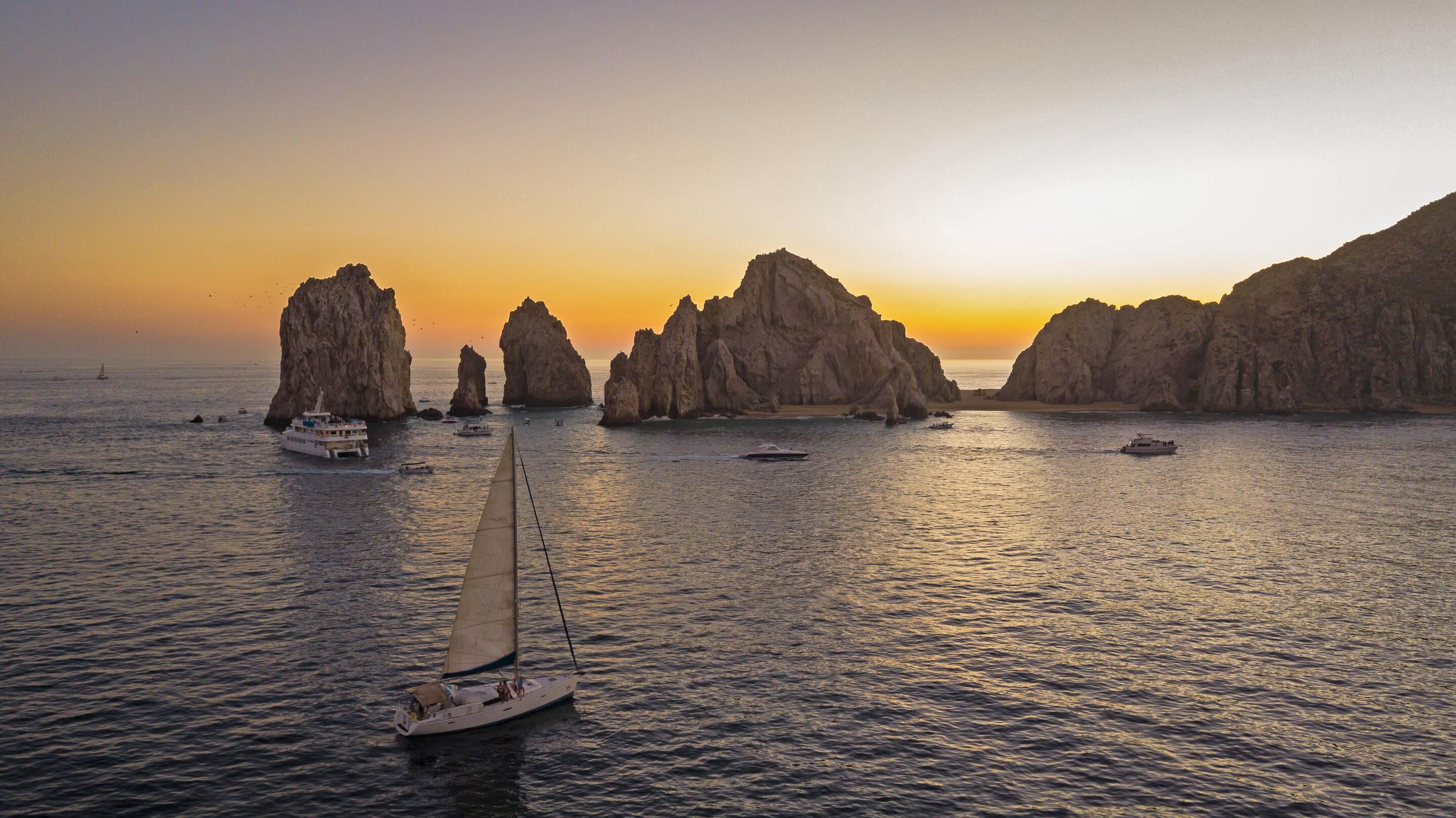 A sailboat on calm waters with rocky formations in the background.