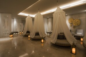 A luxurious bedroom with four canopy beds, each with a lantern, in a modern hotel room.