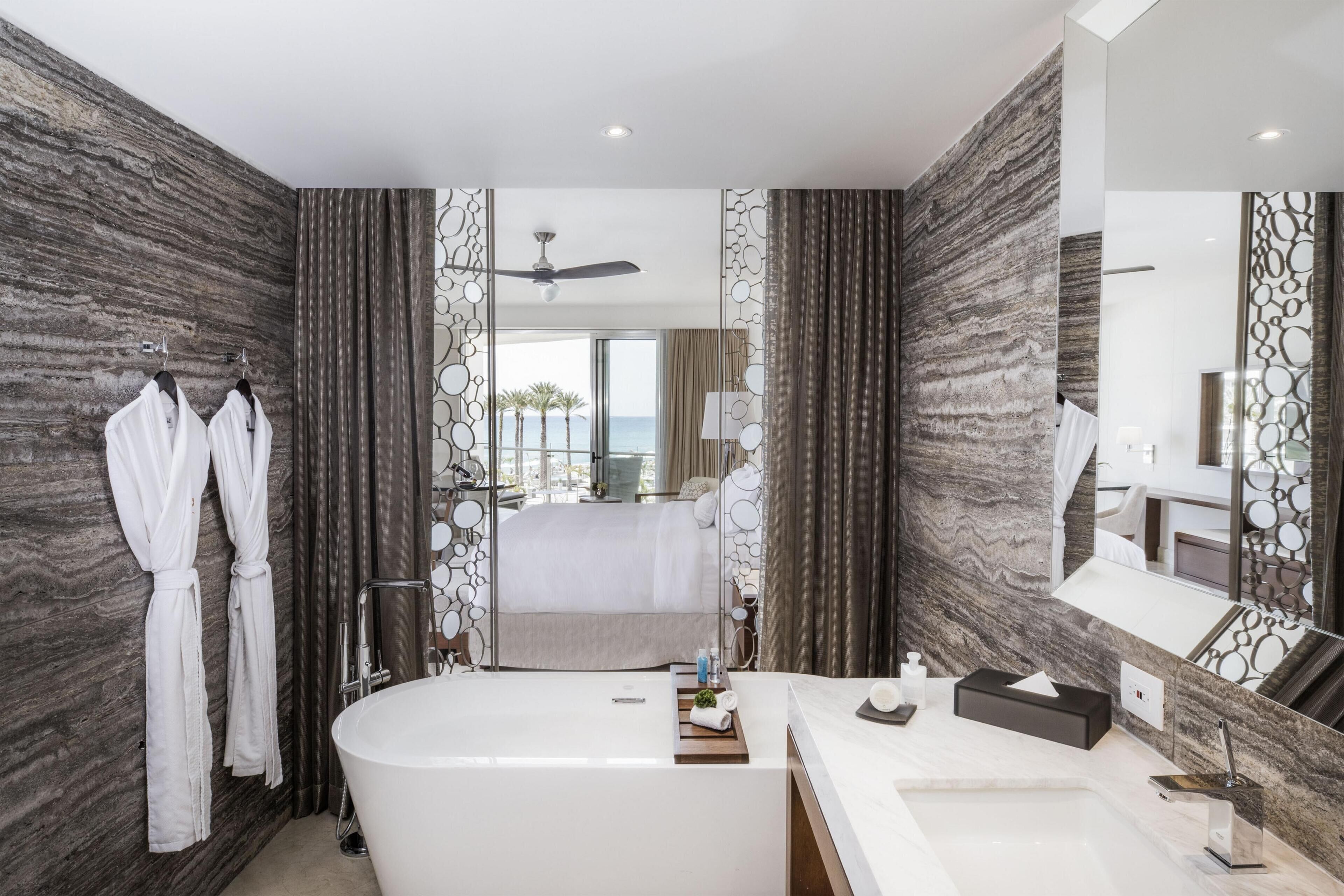 A modern bathroom with a large bathtub, a separate shower area, and a vanity with a mirror.