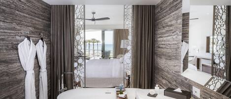 A modern bathroom with a large bathtub, a separate shower area, and a vanity with a mirror.