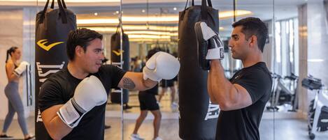 A gym with punching bags, exercise equipment, and a person training.