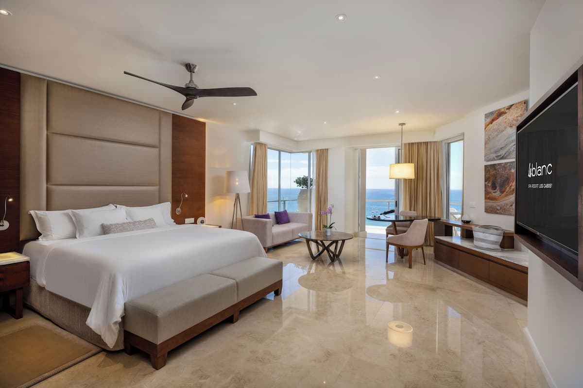 Une chambre d’hôtel moderne dotée d’un grand lit, d’un canapé, d’un coin repas et d’une télévision.