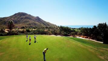 Players tee off amidst a picturesque mountain and ocean view.