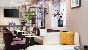 A modern lounge area with seating, a TV, and decorative plants. - Leonardo Boutique Hotel Linz City Center (Linz)