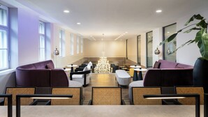 A modern hotel lobby with seating areas, a chandelier, and large windows. - Leonardo Boutique Hotel Linz City Center (Linz)
