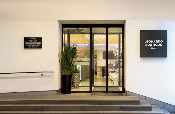 A hotel entrance with a sign for 'Leonardo Boutique Hotel'.
