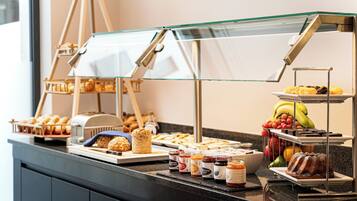 A buffet with various food items including bread, pastries, fruits, and condiments.