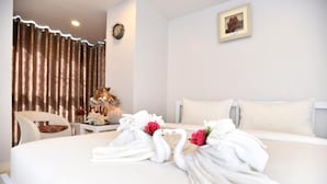 A hotel room with a neatly made bed, a chair, a small table with a lamp, and a curtain. - Parvena Hotel (Bangkok)