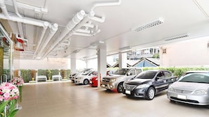 A car dealership with multiple cars on display, a tiled floor, and a clear view of the outside through large windows. - Parvena Hotel (Bangkok)
