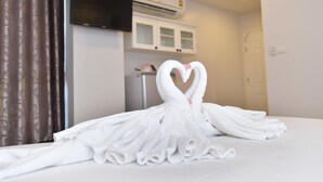 A hotel room with a bed, a TV mounted on the wall, and a white air conditioning unit. - Parvena Hotel (Bangkok)