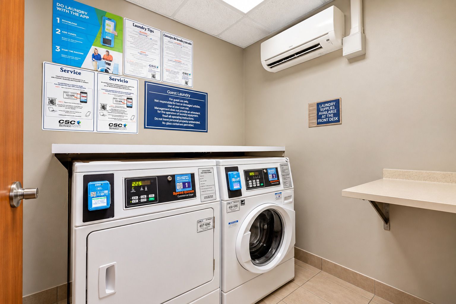 A laundry facility with two front-loading washing machines, a wall-mounted air conditioner, and informational posters.