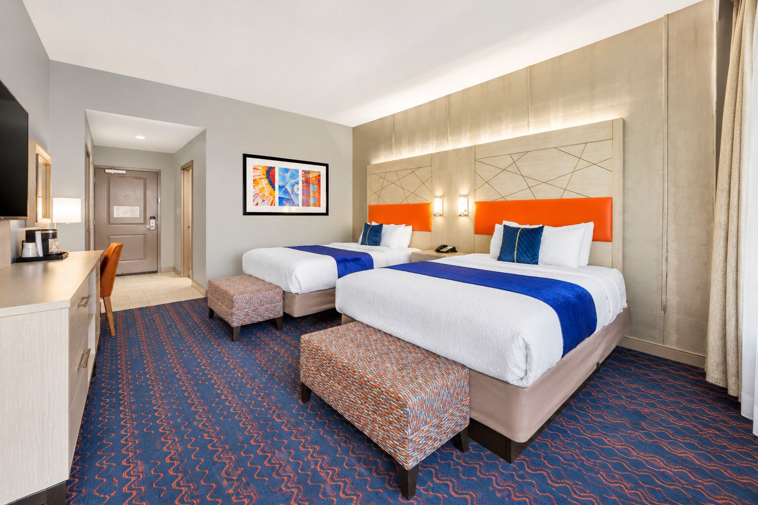 Een hotelkamer met twee bedden, een bureau en een stoel.