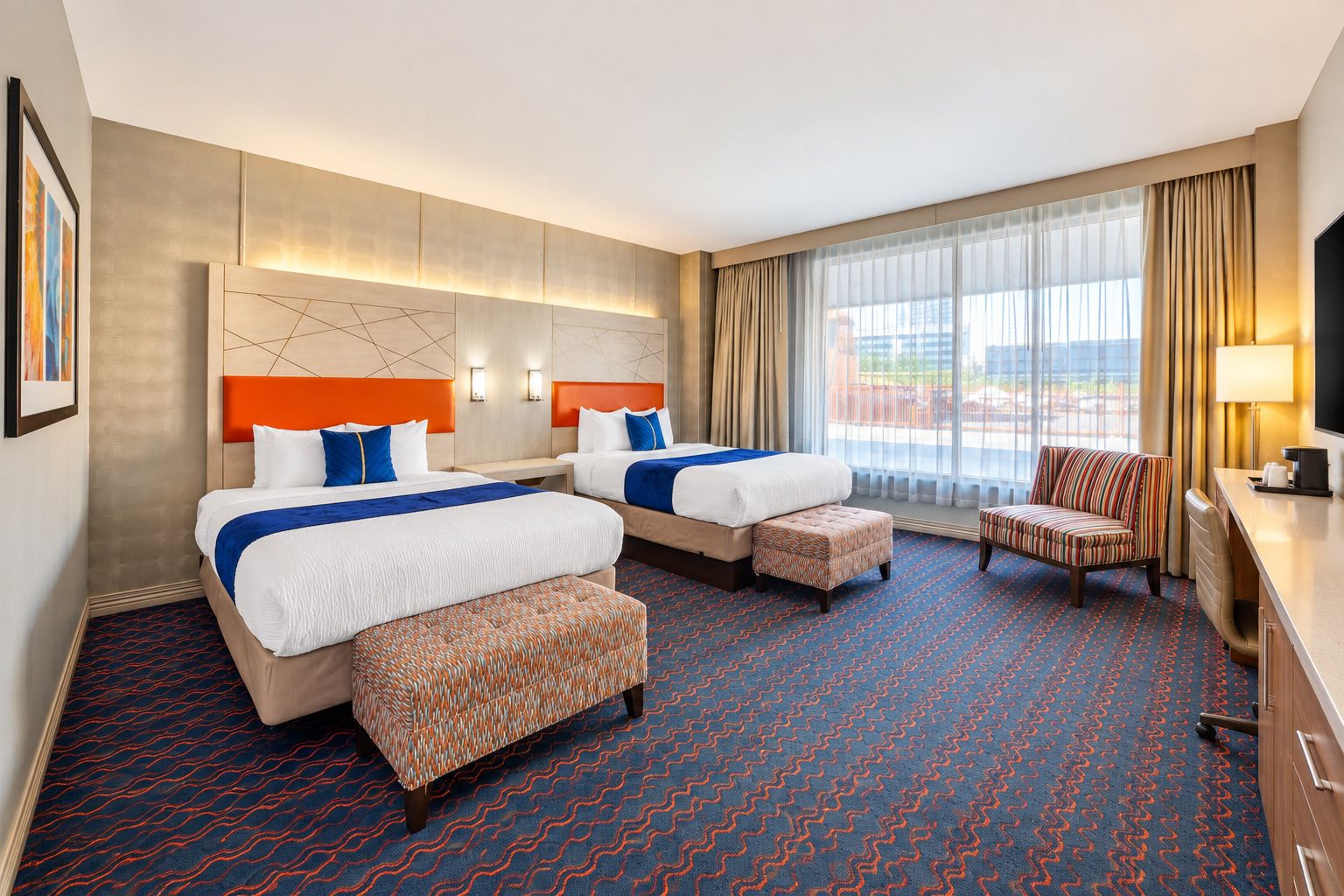 A hotel room with two beds, a sofa, a TV, and a large window with curtains.