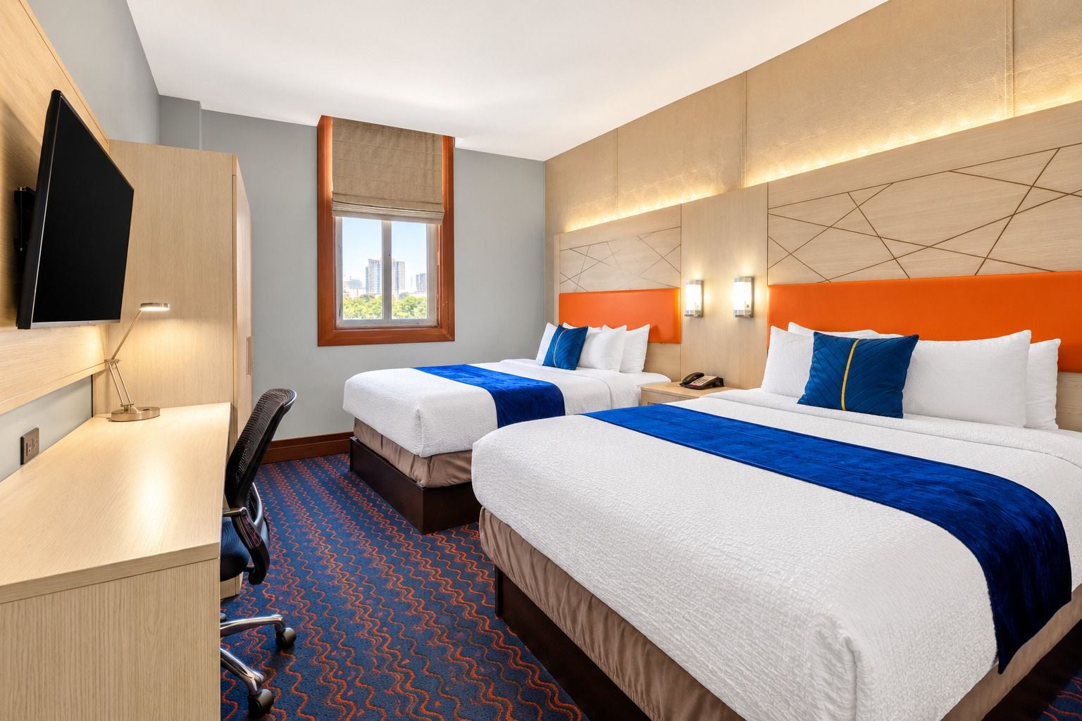Une chambre d’hôtel avec deux lits, un bureau, une chaise, une télévision et une fenêtre donnant sur un beau paysage.